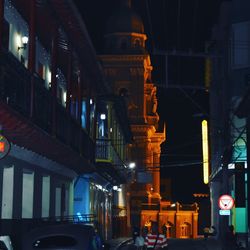 Illuminated street amidst buildings in city at night