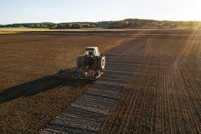 Aerial view of tractor plowing field at sunset
