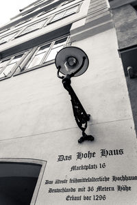 Low angle view of clock hanging on street