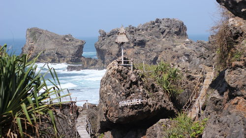 Rock formations by sea against clear sky