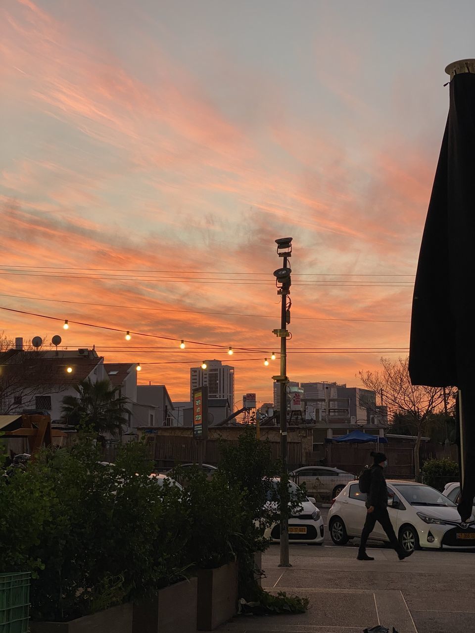 CARS ON ROAD AMIDST BUILDINGS AGAINST SKY DURING SUNSET