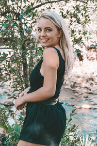 Portrait of smiling young woman standing against plants