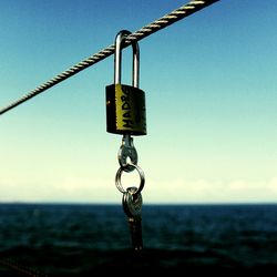 Close-up of key in padlock hanging on metal rope