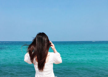 Rear view of woman against sea against clear sky