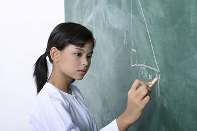 Woman writing on blackboard in classroom
