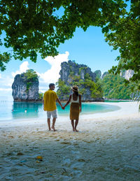 Rear view of woman walking on beach against sky