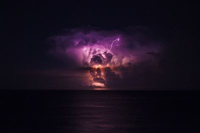 Firework display over sea against sky at night
