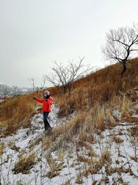 Full length of woman on snow covered field against sky