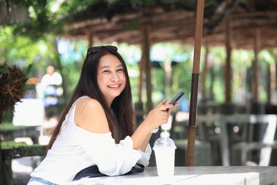 Portrait of young woman using smart phone in restaurant