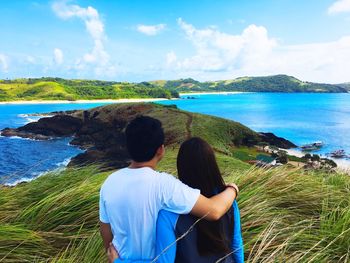 Rear view of couple standing at sea shore against sky