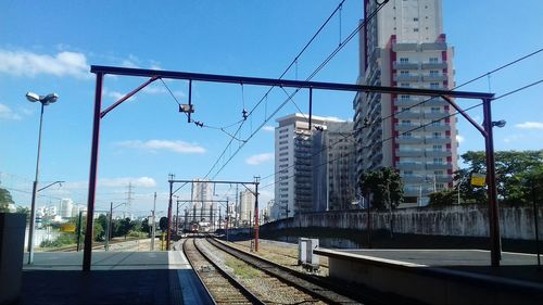 Railroad tracks at station in city against sky