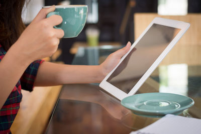 Midsection of man holding coffee cup on table