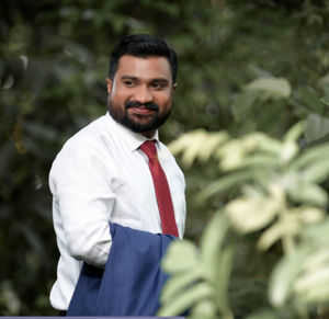 Portrait of young man standing against plants