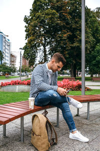 Young man using digital tablet while sitting on bench