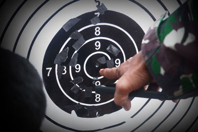 Cropped hand of man pointing at dartboard