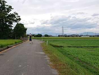 Road amidst field against sky