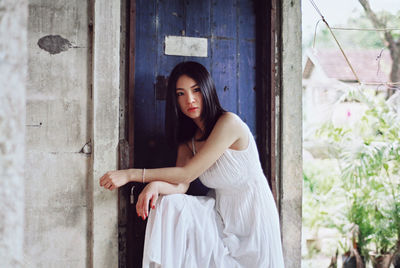 Portrait of young woman standing by door
