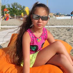 Young woman sitting on sunglasses at beach