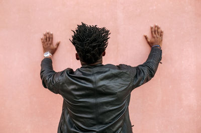 Mid adult man with locs standing in front of pink wall