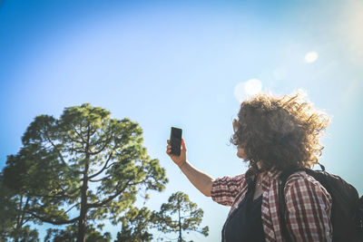 Low angle view of person photographing against sky