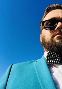 Portrait of man wearing sunglasses against clear blue sky