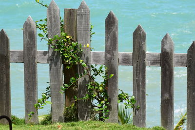 Wooden fence by sea against sky