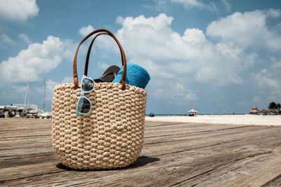 Close-up of bag on wooden walkway against sky