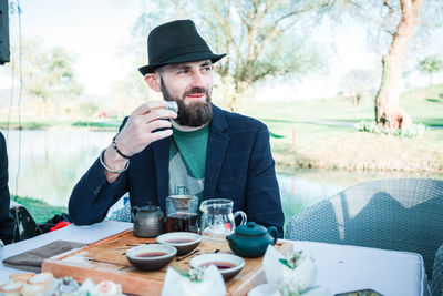 Man looking away while holding tea cup on table