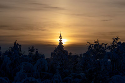 Snow covered land against sky during sunset