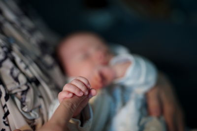 Closeup of newborn baby's hand holding mother's finger