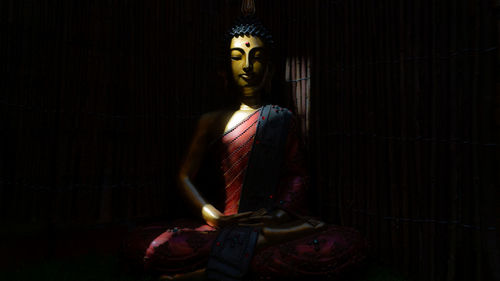 Close-up of buddha statue against black background