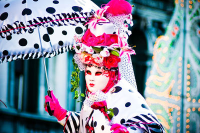 Woman with mask holding umbrella during carnival