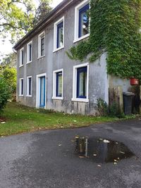 Empty road by house against building