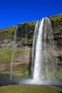 Low angle view of waterfall against clear sky