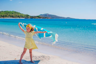Woman standing at beach against blue sky