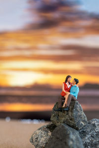 Rear view of woman sitting on rock