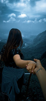 Rear view of woman with hands against sky