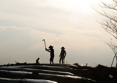 Men working on field against sky during sunset