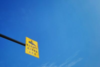 Low angle view of road sign against blue sky