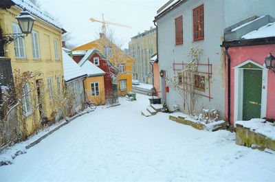 Snow covered street amidst houses and buildings during winter