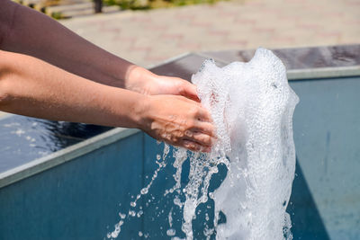 Close-up of hands splashing water at poolside