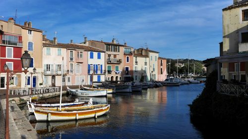 Sailboats moored on canal by buildings in city