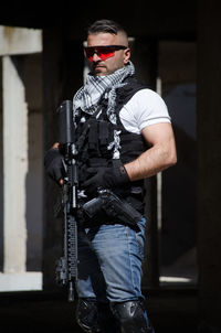 Man holding rifle while standing in building