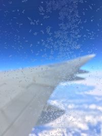 Close-up of airplane window against blue sky