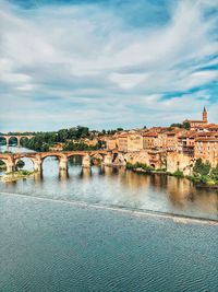 Arch bridge over river against buildings in city