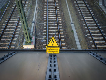 High angle view of high voltage danger sign on railroad tracks