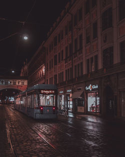 Illuminated street amidst buildings at night