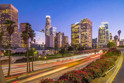 Light trails on street amidst buildings in city against sky