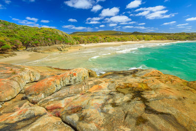 Scenic view of rocks by sea against sky