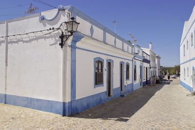 Street amidst buildings against clear blue sky